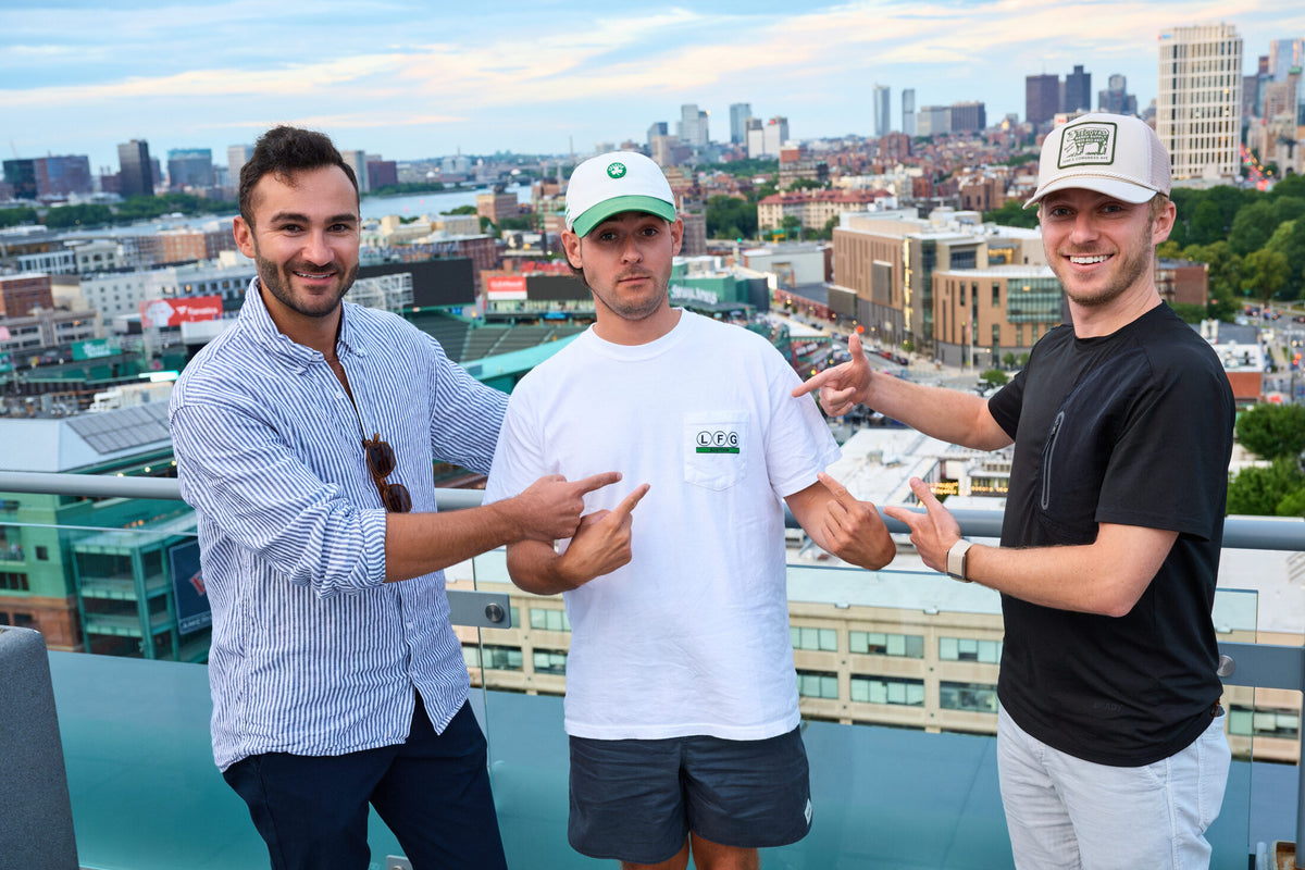 three fans on a rooftop over fenway pointing at the lfg pocket tee